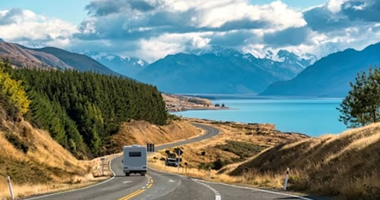 Scenic road trip of Mt Cook or Aoraki over winding road with motorhome driving and Lake Pukaki on sunny day at Peters lookout, New Zealand