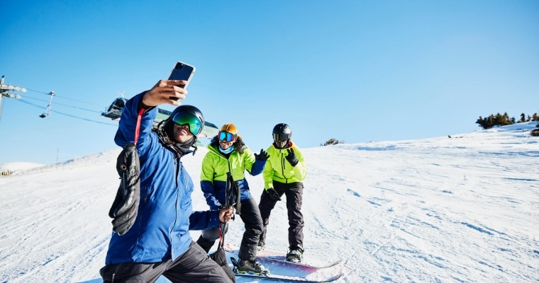 A group of people on snowboards taking a selfie halfway down them mountain