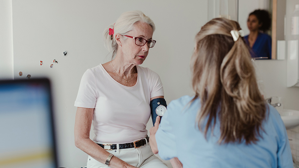 A woman getting her blood pressure taken by a female doctor.