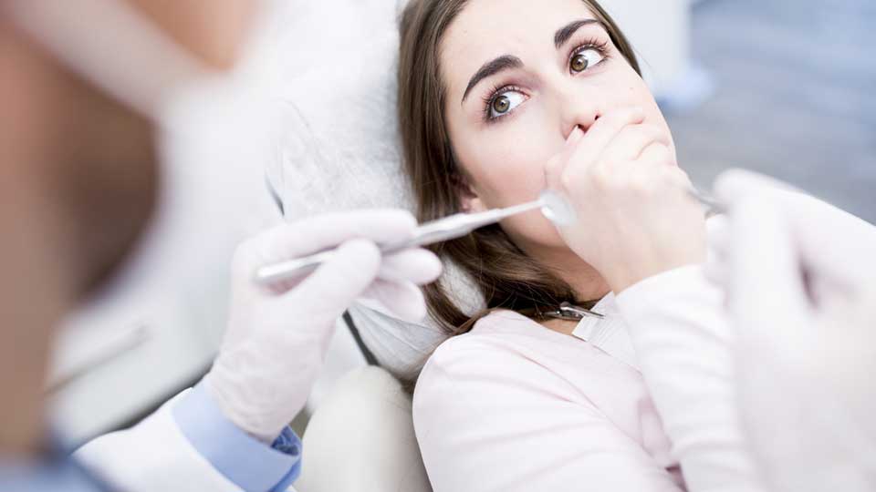 Woman be afraid of dentist in dentist chair. 