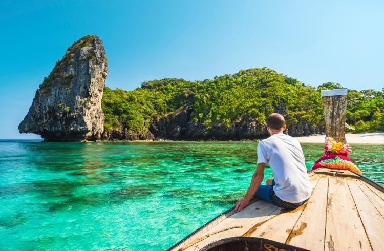 A man sitting on a boat in a bay in Thailand