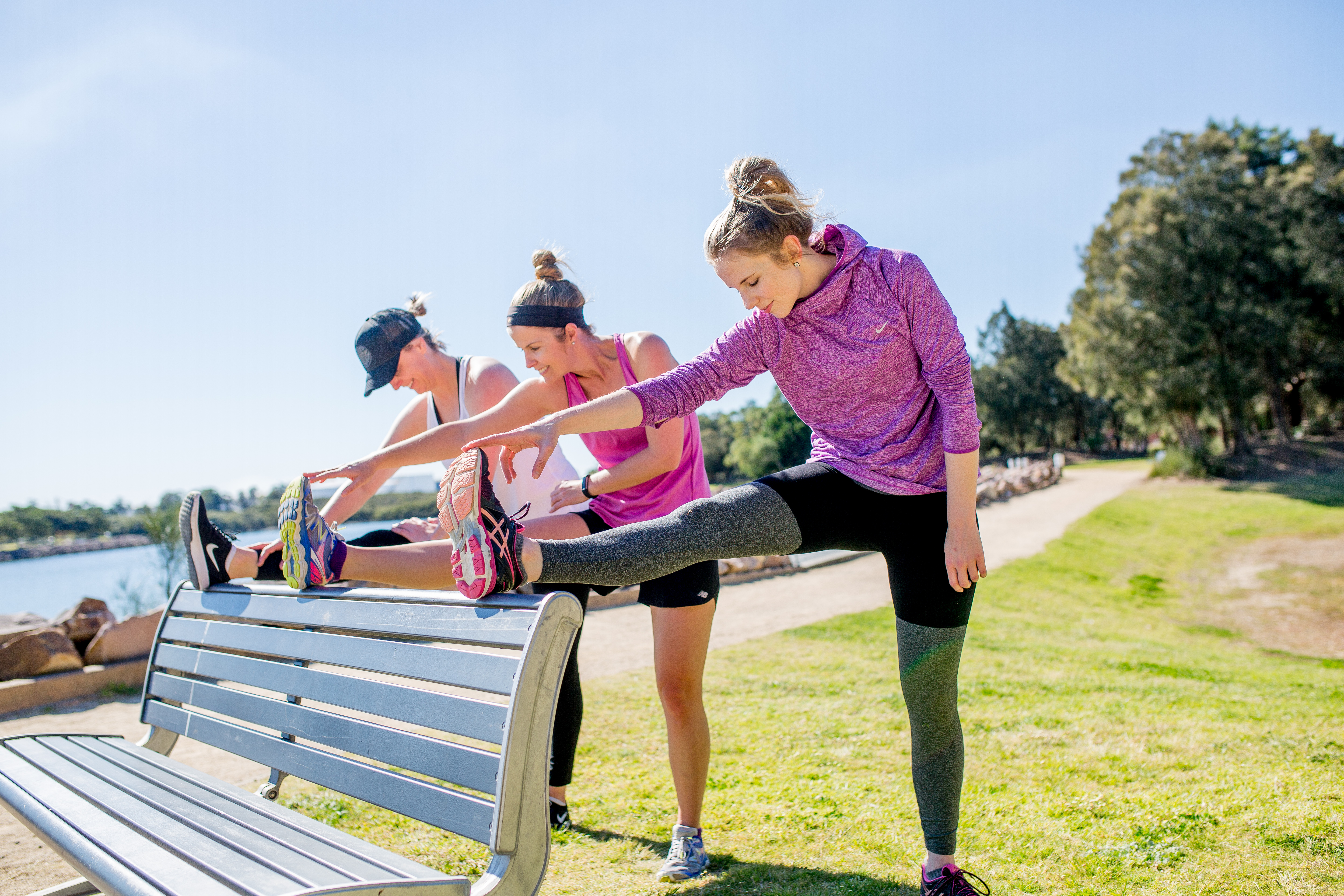 Three women stretching their legs on a bench in the park