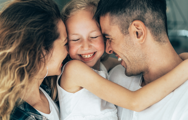 Mother and father embracing their daughter