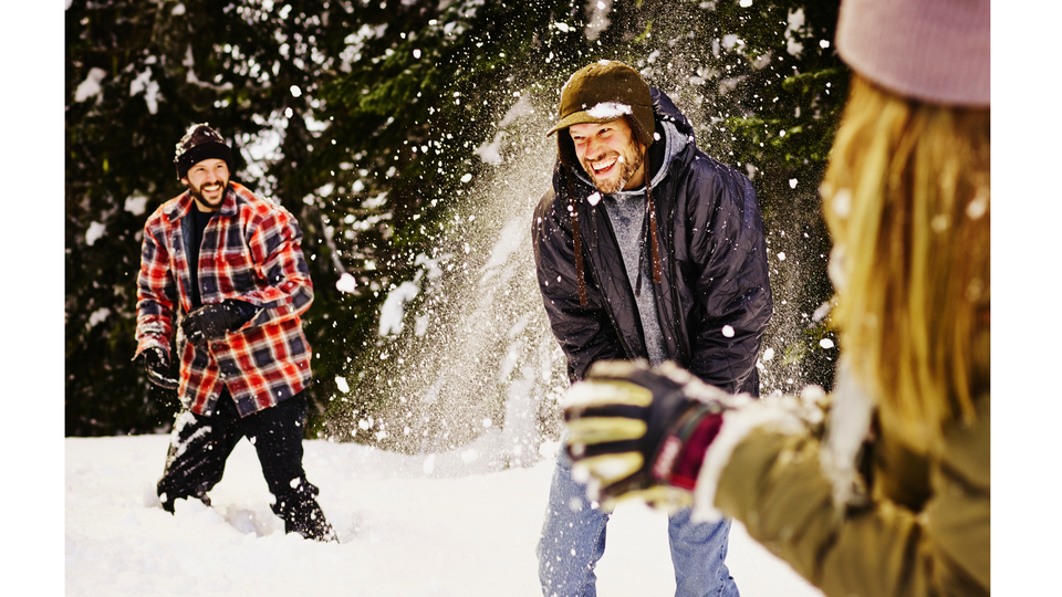 Young trio throwing snowballs at each other laughing.