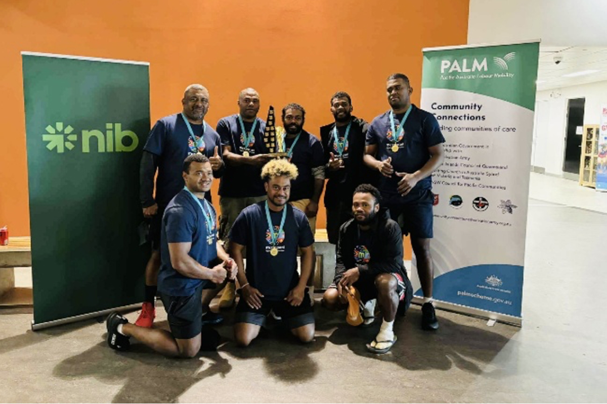 PALM workers wearing sports medals standing infront of nib and PALM posters