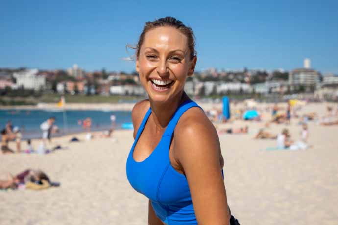 Casey Maynard on the beach wearing a blue top.