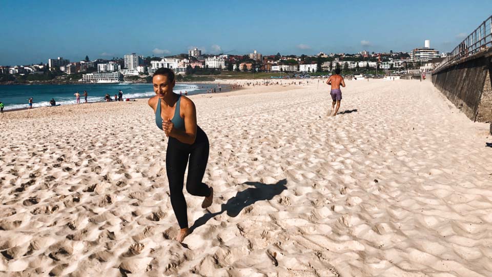 A person doing skaters exercises on a beach.