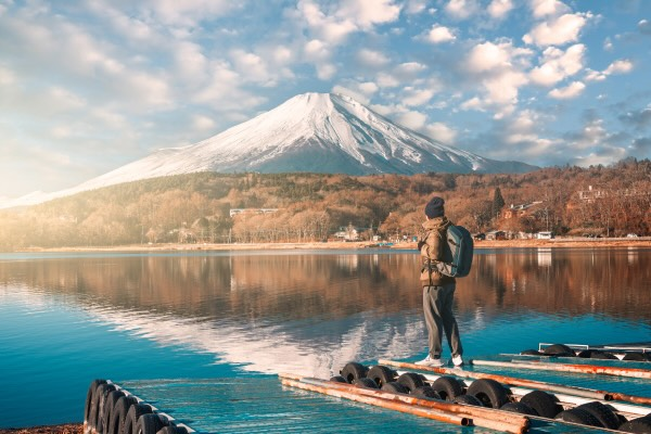 A person standing on a wharf looking at a mountain peak in the distance