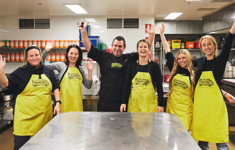 5 female nib employees volunteering at OzHarvest kitchen. Chef in the middle