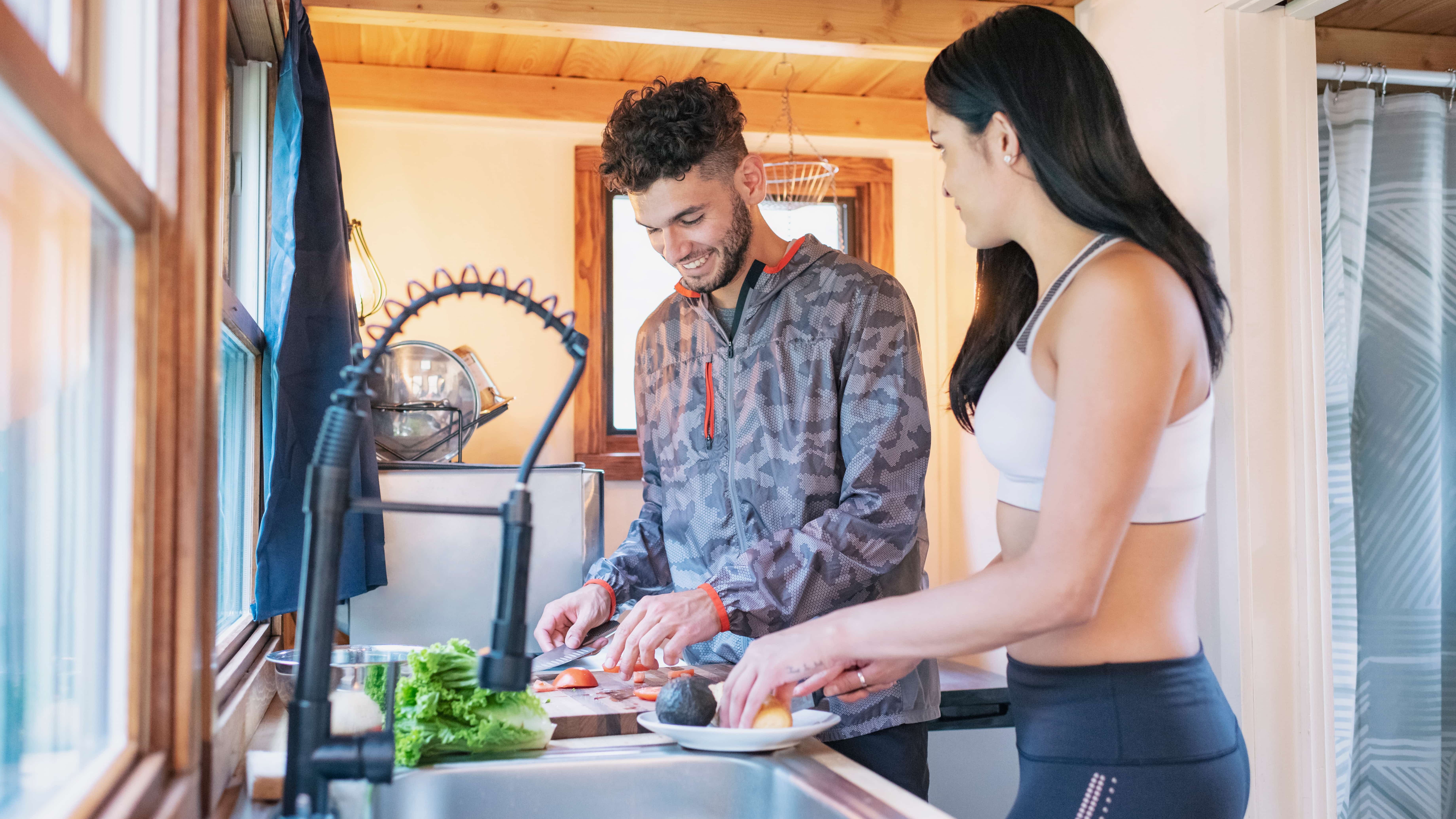 Young couple preparing meal in kitchen of tiny house.