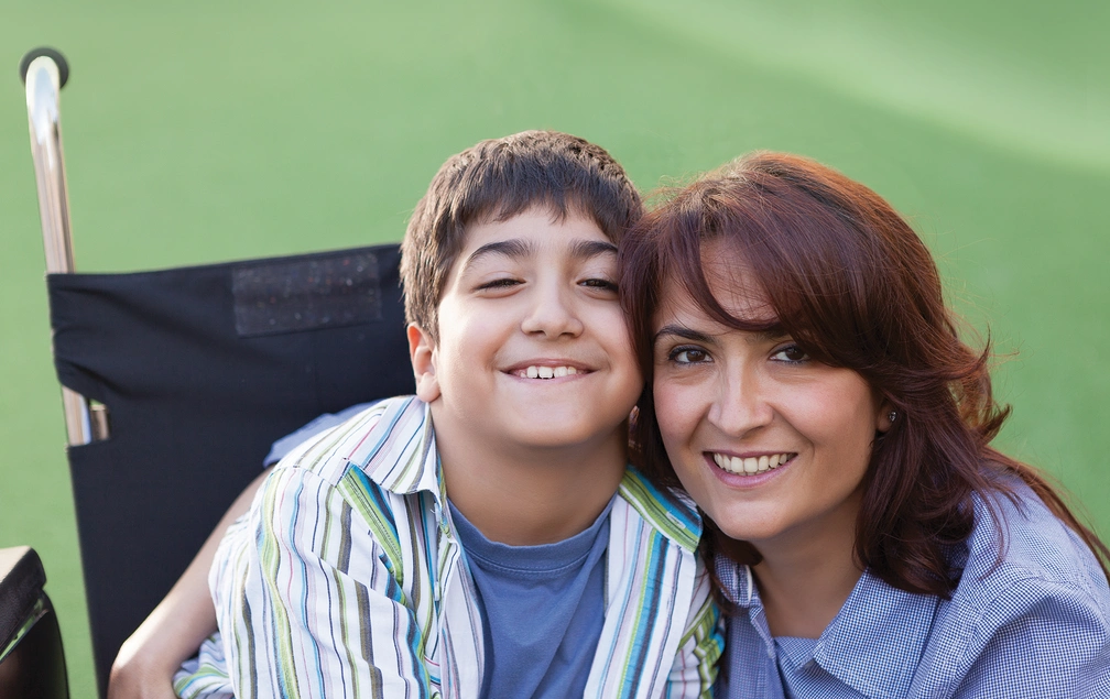 Boy in a wheelchair smiling with his mum
