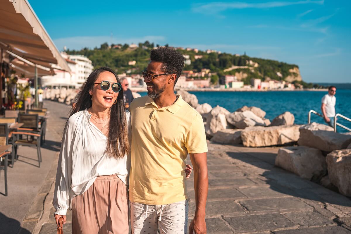 A man and a woman smiling and walking with their arms around each other on a waterfront pier