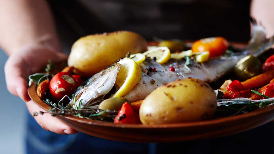 A plate with fish, potatoes and vegetables.