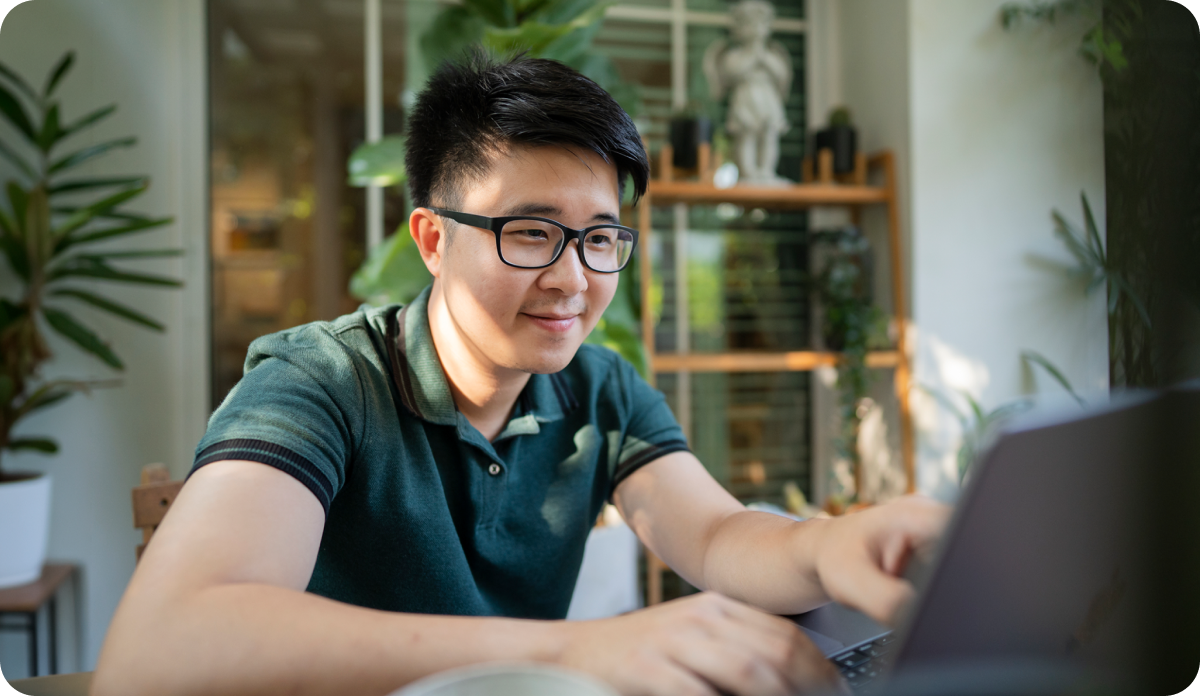 Man wearing glasses working on the laptop outside.