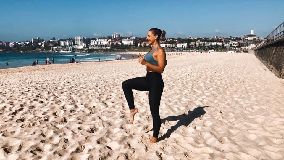 A person doing high knees on a beach.