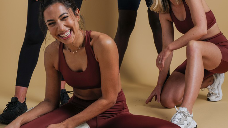 Brooke Jowett stretching on a gym floor wearing maroon activewear.