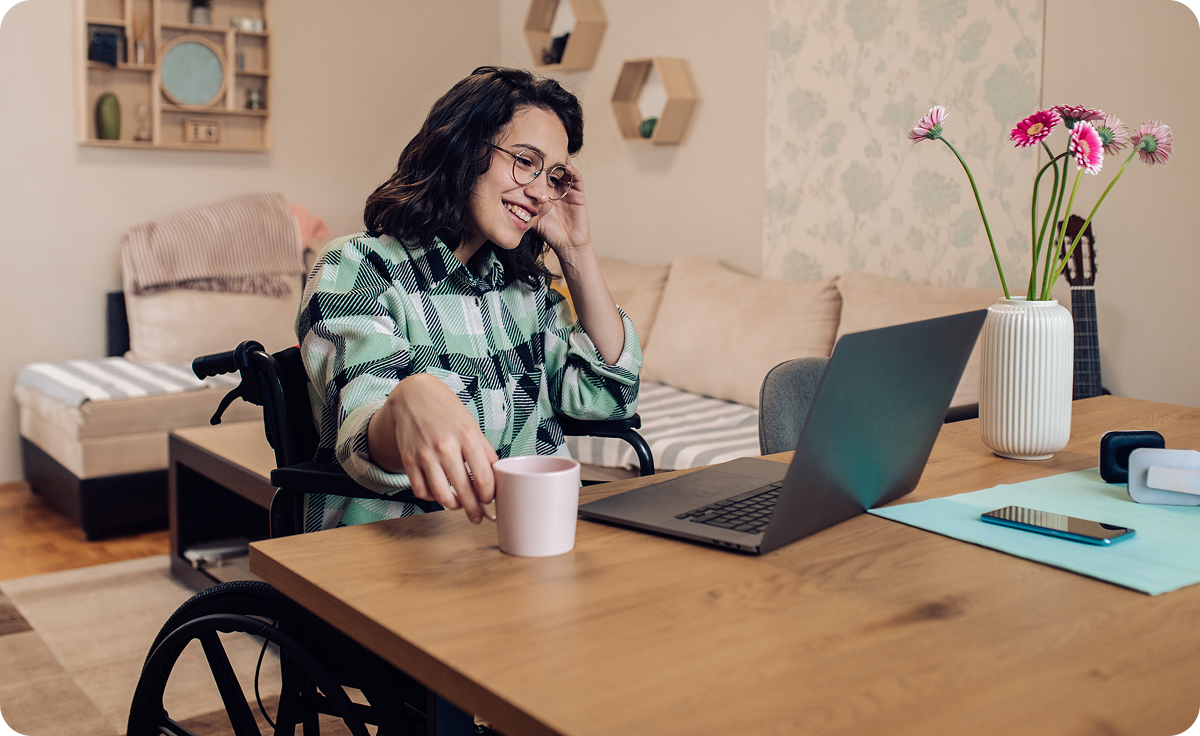 A smiling woman in a wheelchair using a laptop