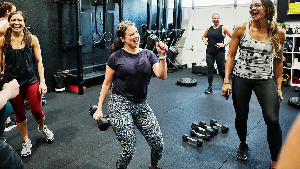 A group of women doing weights at the gym, laughing.