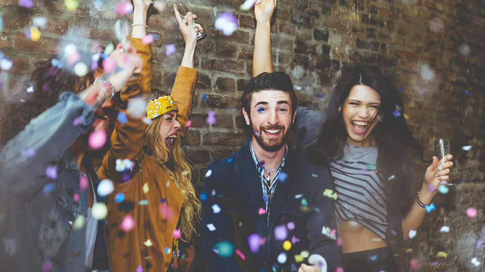 Four people celebrating with confetti raining down on them.