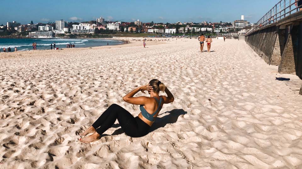 A person doing crunches on a beach.