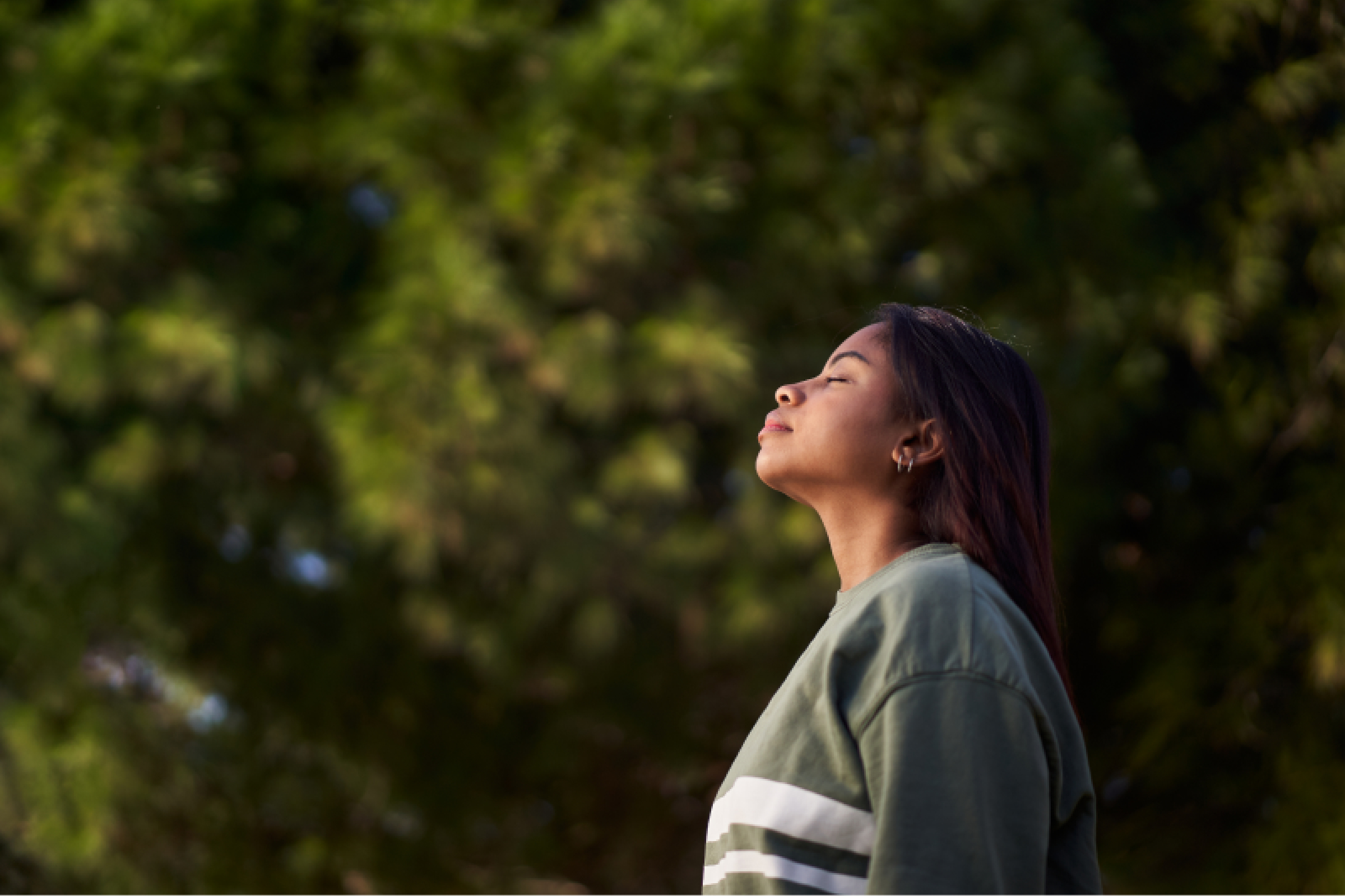 Woman in nature with head tilted up to the sun