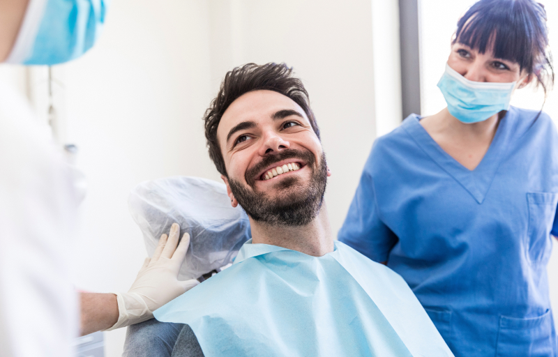 Smiling male patient with female dentists at medical clinic