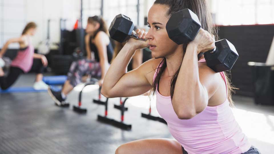 A woman lifting dumbbells at a gym.