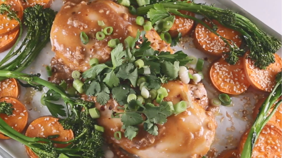 Satay chicken on a plate with vegetables and spring onion garnish.