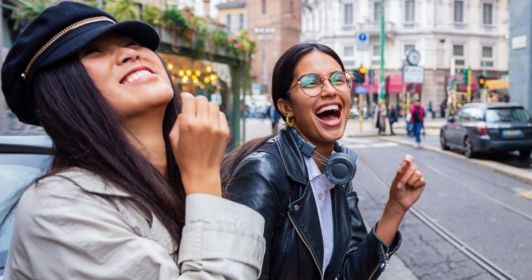 Two girls laughing and smiling in the street
