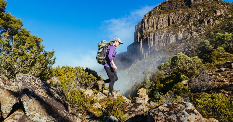 A woman hiking in mountains wearing a hiking backpack
