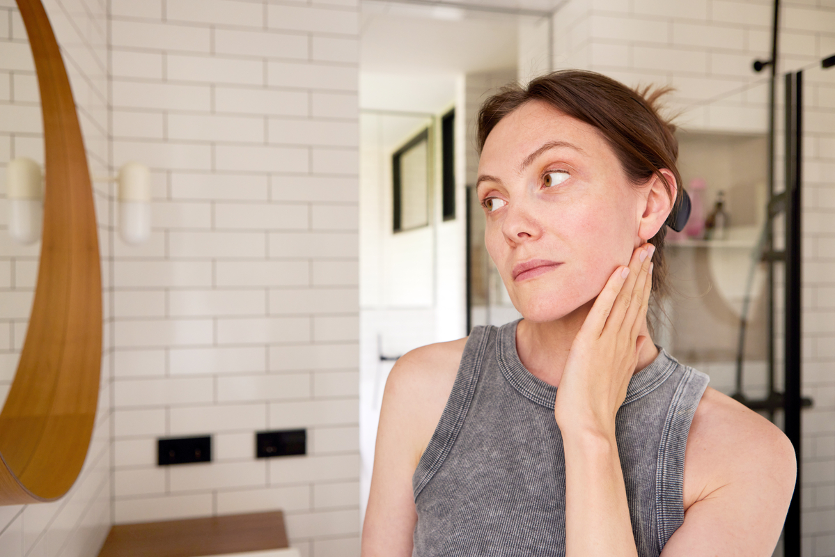 Person rubbing their face while looking in the mirror.