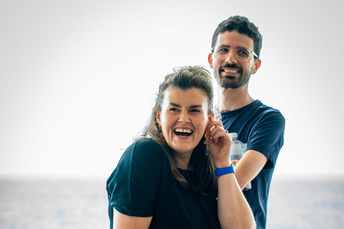 Two people standing next to each other, both are laughing.