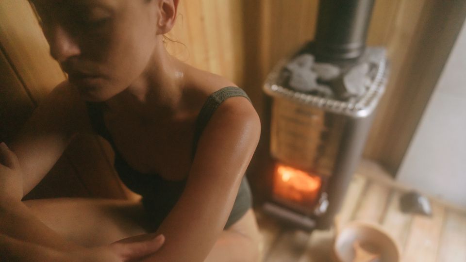 Person sitting in a relaxed position inside a traditional wood-panelled sauna.