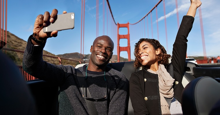 A smiling couple driving across a bridge in the USA