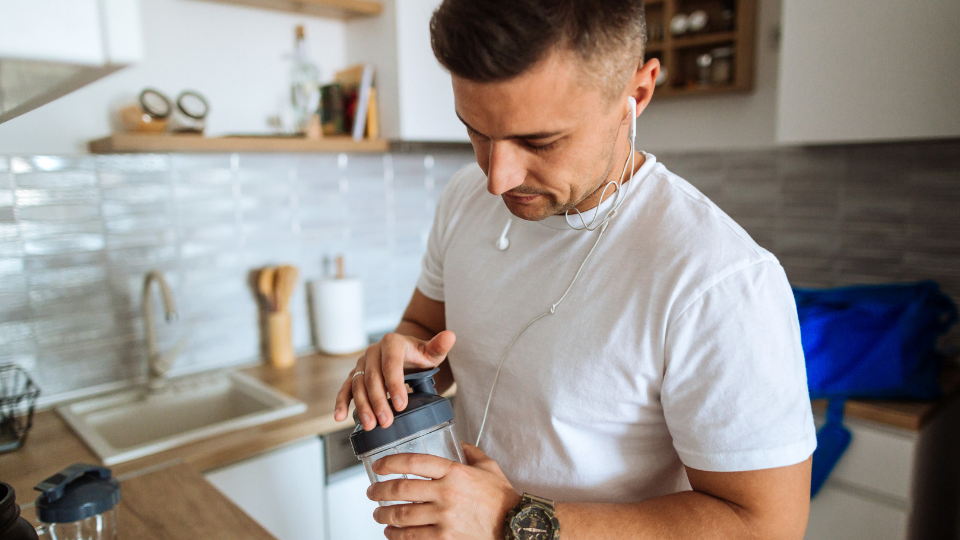 A man puts together a protein shake in a kitchen