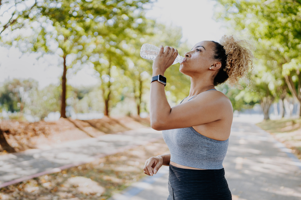 Woman taking a break from a run to drink a bottle of water