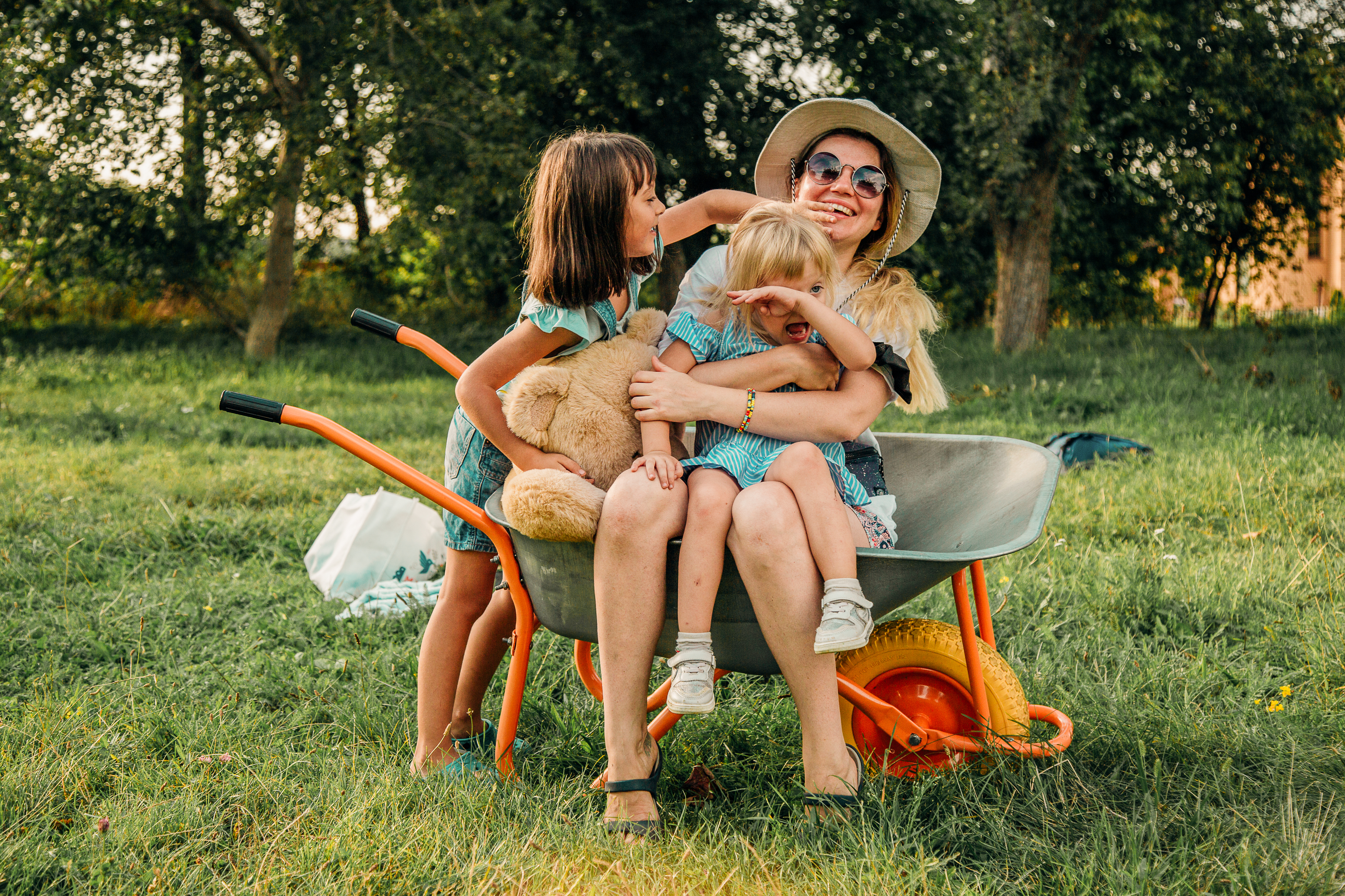 Young mother playing with kids in a wheelbarrow