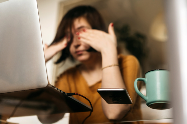 A woman sitting at a glass table. She is rubbing her eyes as if she is tired.