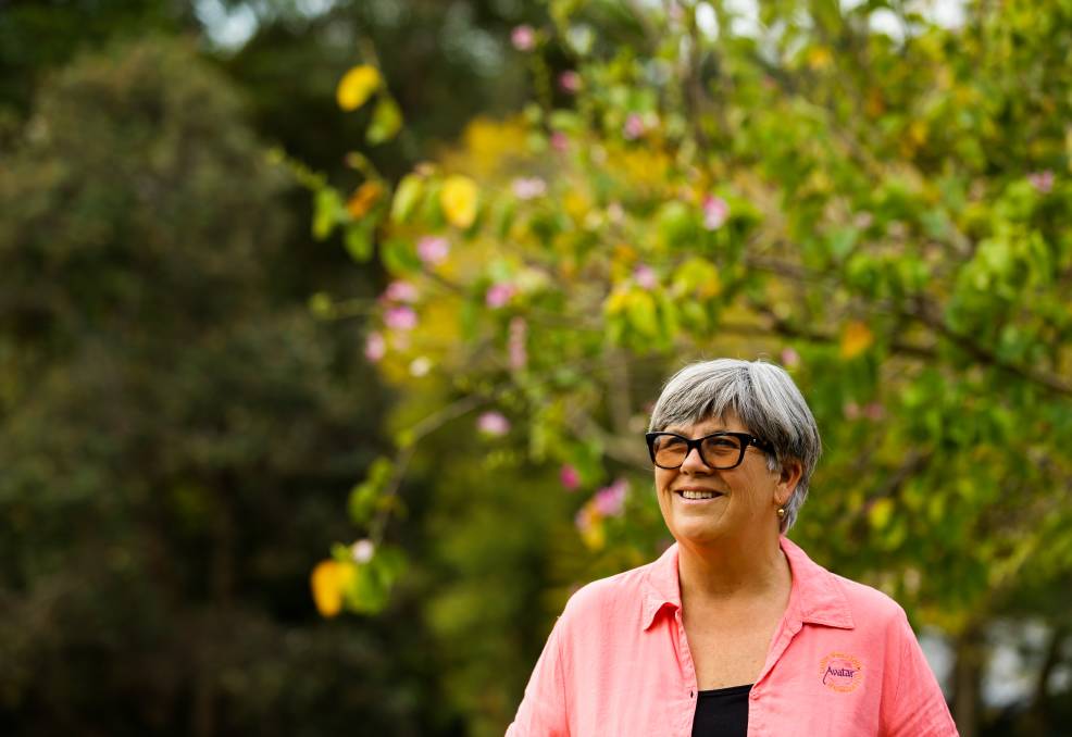 Woman wearing a bright pink shirt and sunglasses out in nature