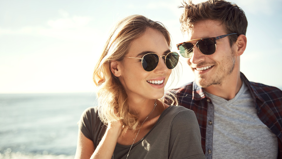 A couple wearing sunglasses smile as they enjoy the sunshine.