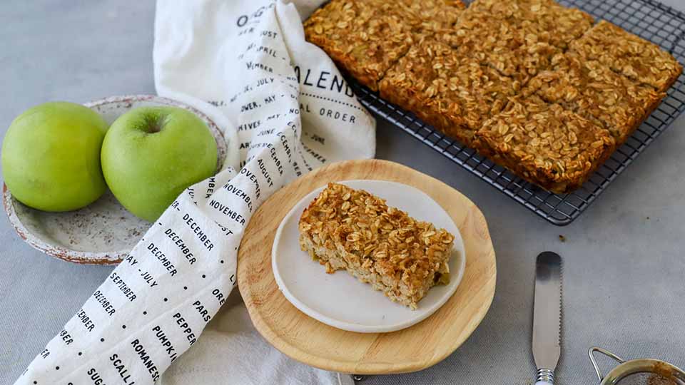 Apple and cinnamon bars plated on saucer, with green apples on the side.