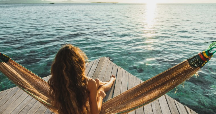 A woman lounging in a hammock in front of the ocean