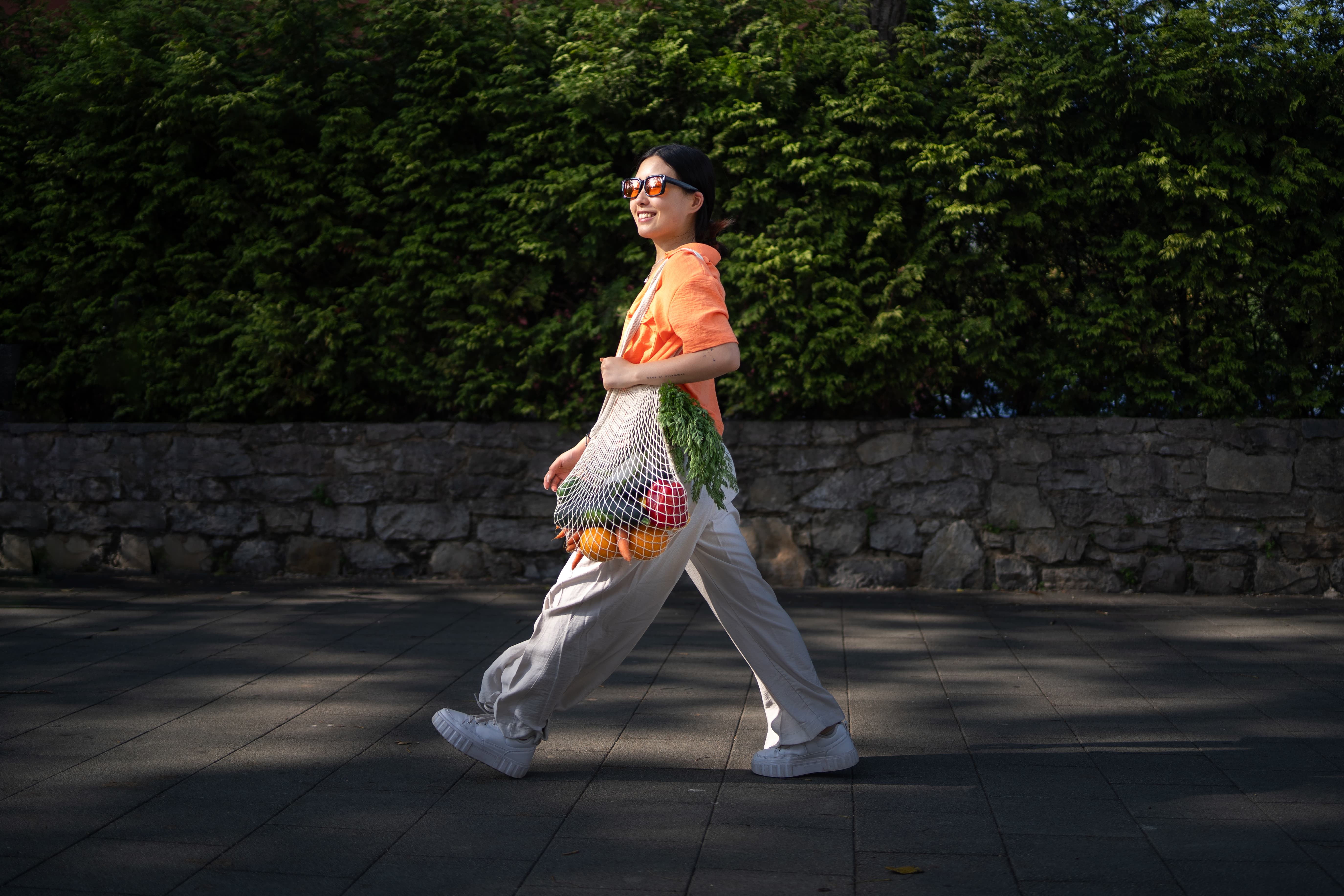 Person walking with a bag of fruit and vegetables.