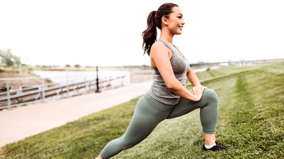 A young girl doing a lunge on the side of a hill