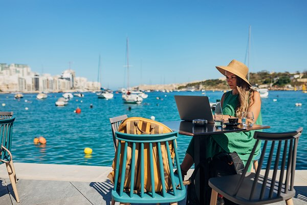 A digital nomad working on a laptop on a desk in front of the water