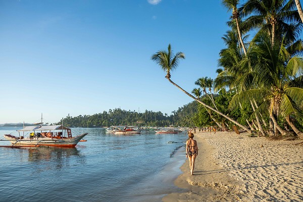 A woman walking along a beach in Palawan, The Philippines