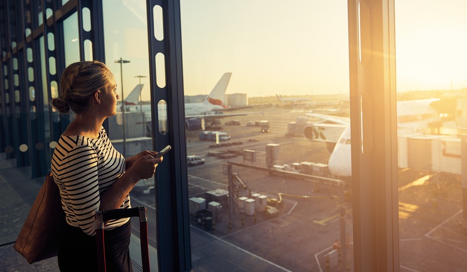 Woman at airport looking out window.