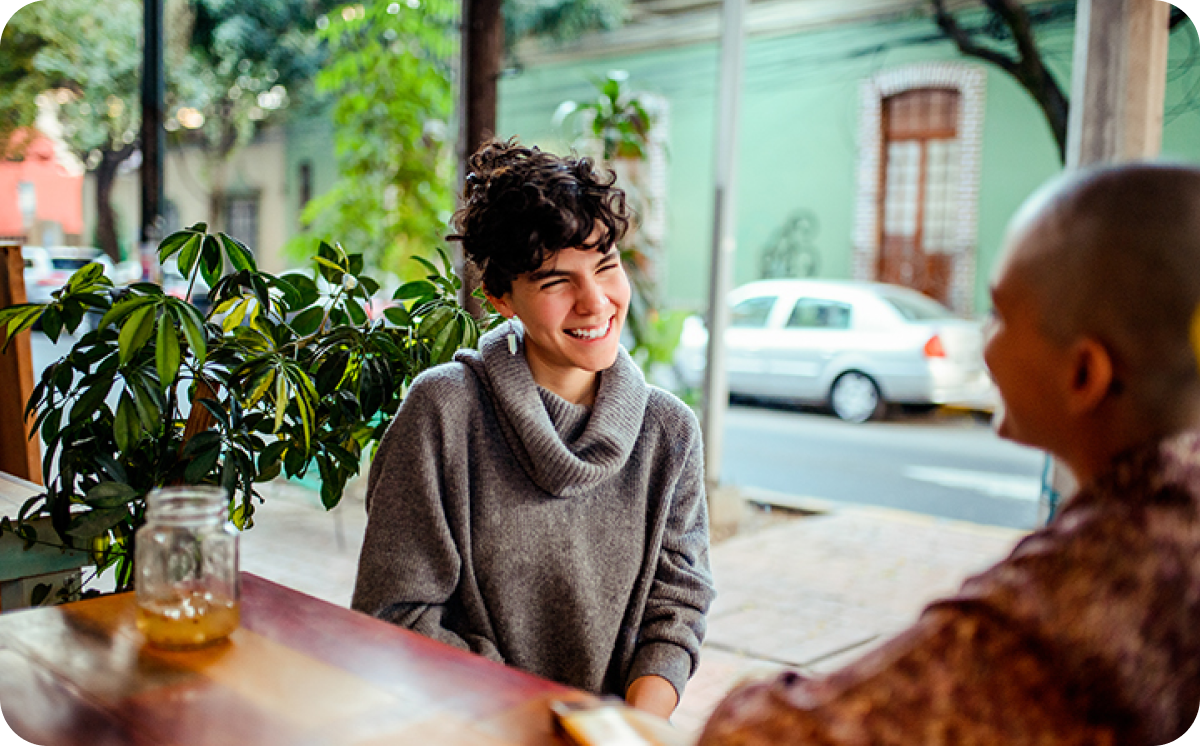 Two women smiling at each other at a cafe