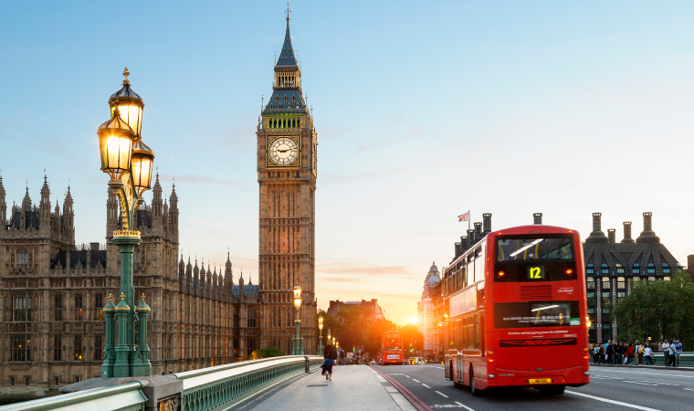 A red bus driving in front of Big Ben in London