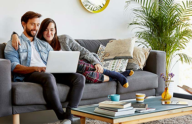 Man and woman sitting on couch looking at laptop